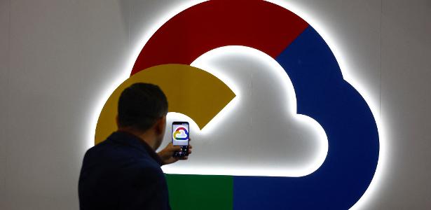 Pessoa tira foto em frente ao logotipo do Google Cloud, o serviço da nuvem da empresa