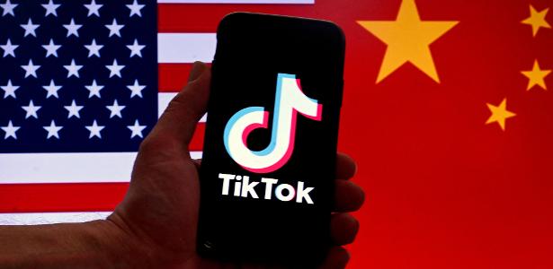 Celular com logo do TikTok e bandeiras dos EUA e da China ao fundo