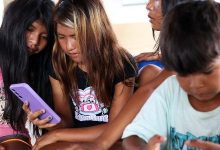 11.dez.2025 - Crianças indígenas usam celulares na aldeia Apyterewa, no Pará