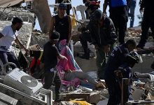 Equipes de resgate e moradores cobrem um corpo em meio aos escombros após terremoto na Venezuela.