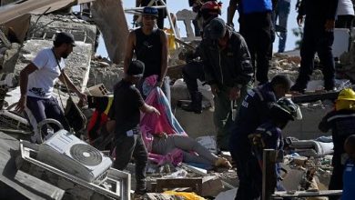 Equipes de resgate e moradores cobrem um corpo em meio aos escombros após terremoto na Venezuela.