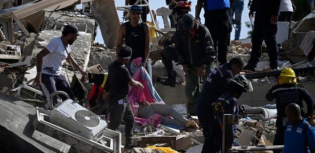 Equipes de resgate e moradores cobrem um corpo em meio aos escombros após terremoto na Venezuela.