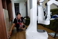 Esta foto, tirada em 21 de maio de 2026, mostra uma diarista fazendo a limpeza ao lado de um robô da X Square na casa de um cliente em Pequim