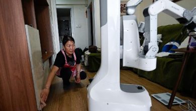 Esta foto, tirada em 21 de maio de 2026, mostra uma diarista fazendo a limpeza ao lado de um robô da X Square na casa de um cliente em Pequim