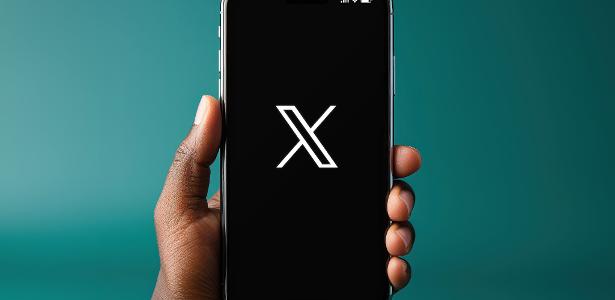 Pessoa segurando um iPhone X com o logo da rede social X