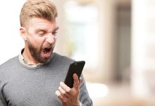 Homem com celular smartphone e expressão de raiva ódio nervoso