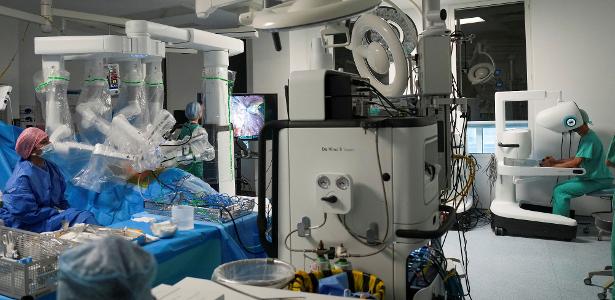 Esta foto, tirada em 3 de julho de 2026, mostra o cirurgião Sasha Stamenkovic (à extrema direita) -- diretor de cirurgia robótica, pesquisa e programas de especialização -- realizando uma cirurgia de câncer de pulmão com o novo sistema cirúrgico assistido por robô Da Vinci 5, com o auxílio de enfermeiros (à esquerda), no Hospital St. Bartholomew, em Londres